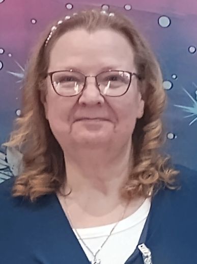 Smiling woman with glasses and curly hair against a colorful background.