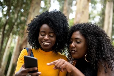 TWO WOMEN LOOKING AT SMARTPHONE SCREEN