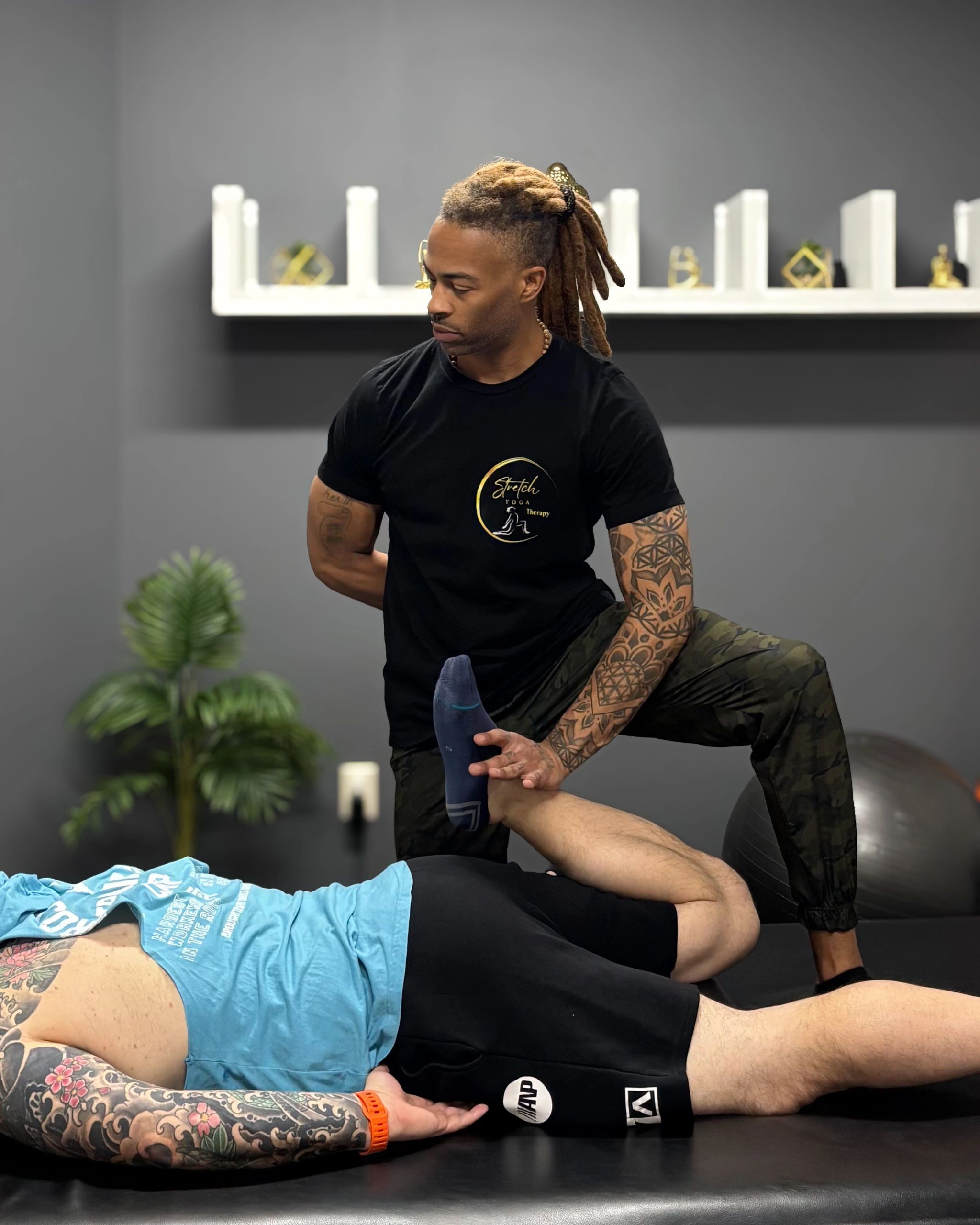 A therapist assists a client with a leg stretch during therapy session.