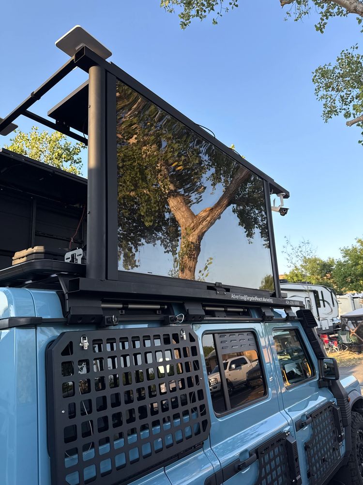 Blue vehicle equipped with a large digital billboard on the roof.