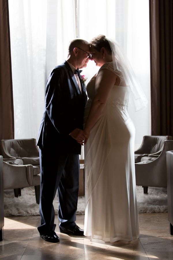 Bride and groom share a tender moment in soft backlight.