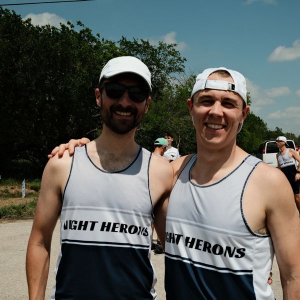Two men in matching 'Night Herons' athletic shirts smiling outdoors.