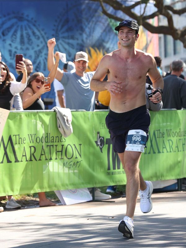 Shirtless runner smiling while participating in The Woodlands Marathon.