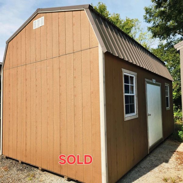 Brown wooden storage shed with a metal roof and 'SOLD' sign.