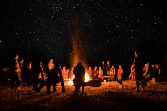 Group sitting around a campfire under a starry sky.