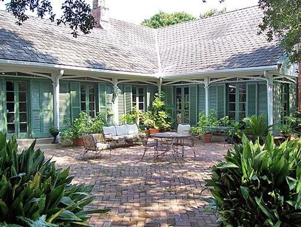 Cozy patio with brick flooring and green shutters on a classic house.