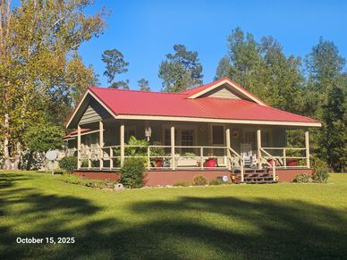 Cozy house with red roof and green lawn under clear sky.
