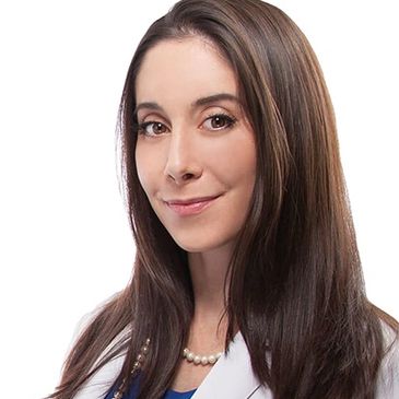 Professional woman with long brown hair wearing a white coat and pearl necklace.