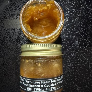 Open jar of amber cannabis concentrate next to sealed jar with label.