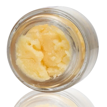Close-up of a creamy, yellow substance in a clear glass jar.