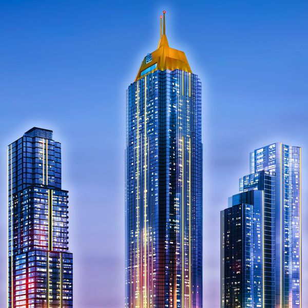Tall skyscraper with a gold crown lit up at dusk.
