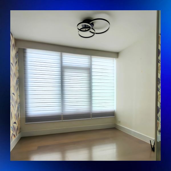 Empty room with large window and modern ceiling light.