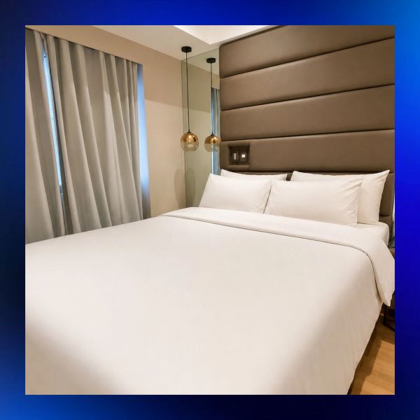 Modern bed with soft headboard and gold pendant lights.
