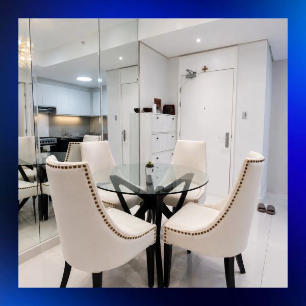 Modern dining area with glass table and white chairs.