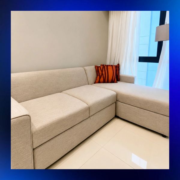 Beige sectional sofa with one decorative pillow.