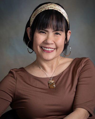 Smiling woman with hoop earrings and a patterned headband.