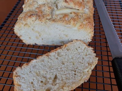 Freshly baked loaf of bread with a slice cut, resting on a cooling rack.