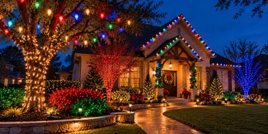 Festive Christmas lights decorating a house and yard at night.