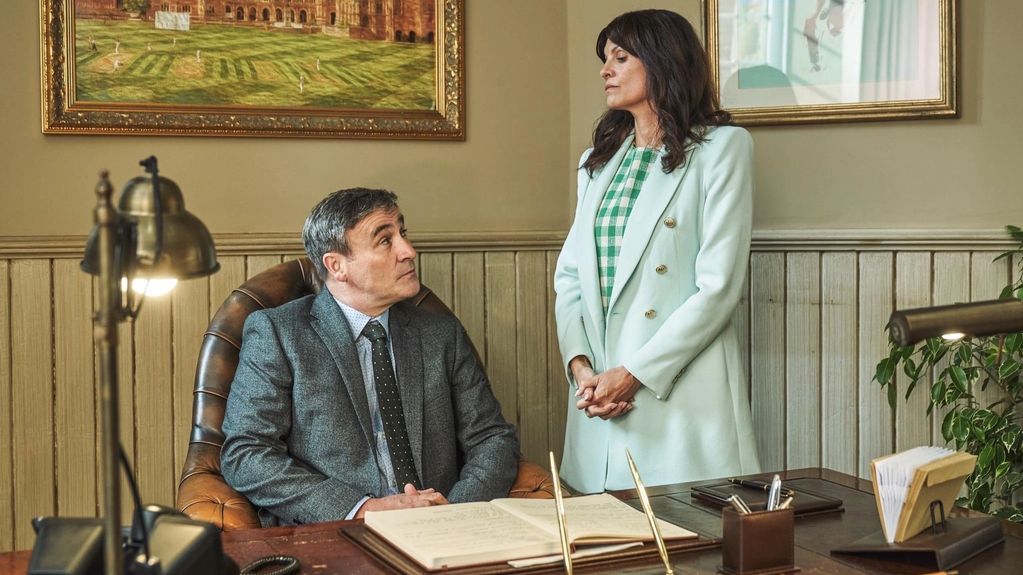 Man sitting and woman standing in an office setting.