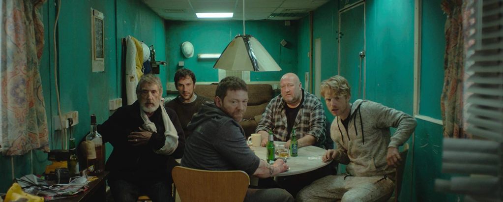 Five men sitting around a table in a dimly lit room.