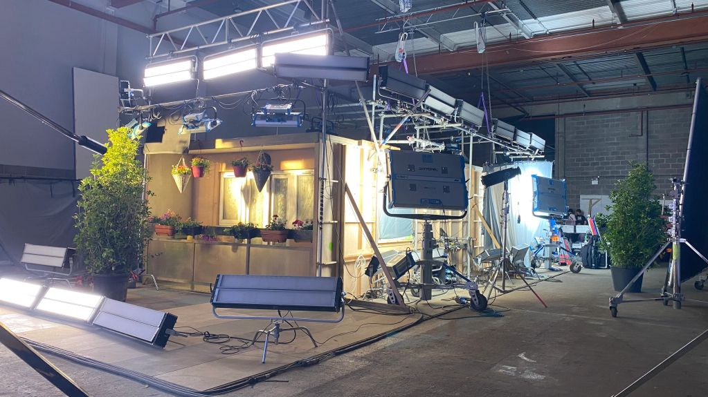 Indoor film set with lighting and plants.