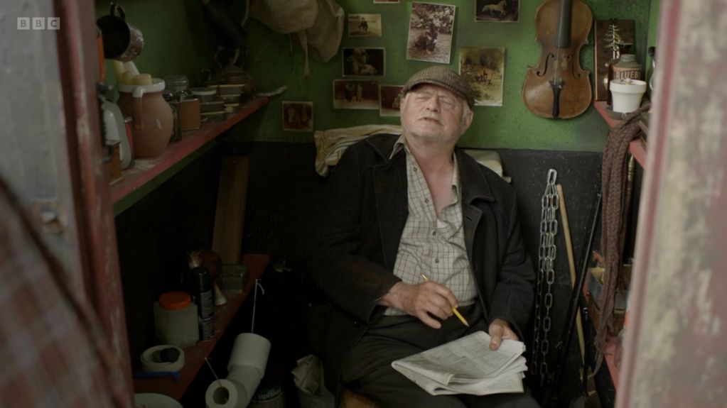 Man sitting in a small room with a notebook and pencil.