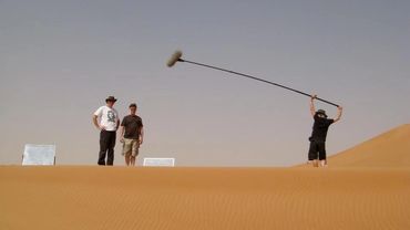 Three men on a sand dune with a boom mic and reflectors.