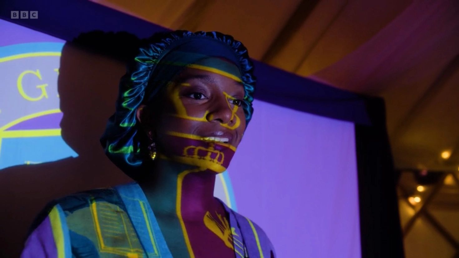 Person with colorful projections on their face and clothing.