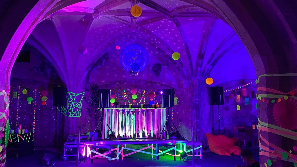 A vibrant neon-lit party setup with decorations and DJ booth.