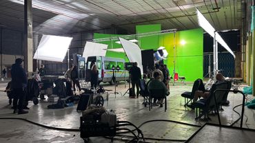 Film crew working on a set with green screen and lighting.