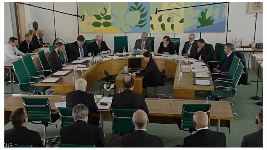 A formal meeting with attendees reviewing documents.
