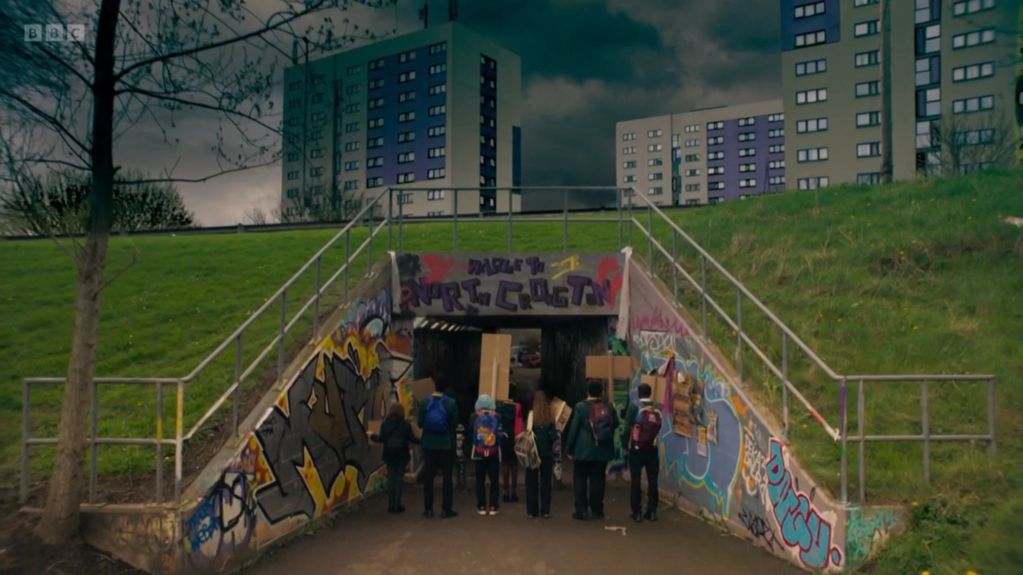Group of people entering a graffiti-covered underpass in an urban area.