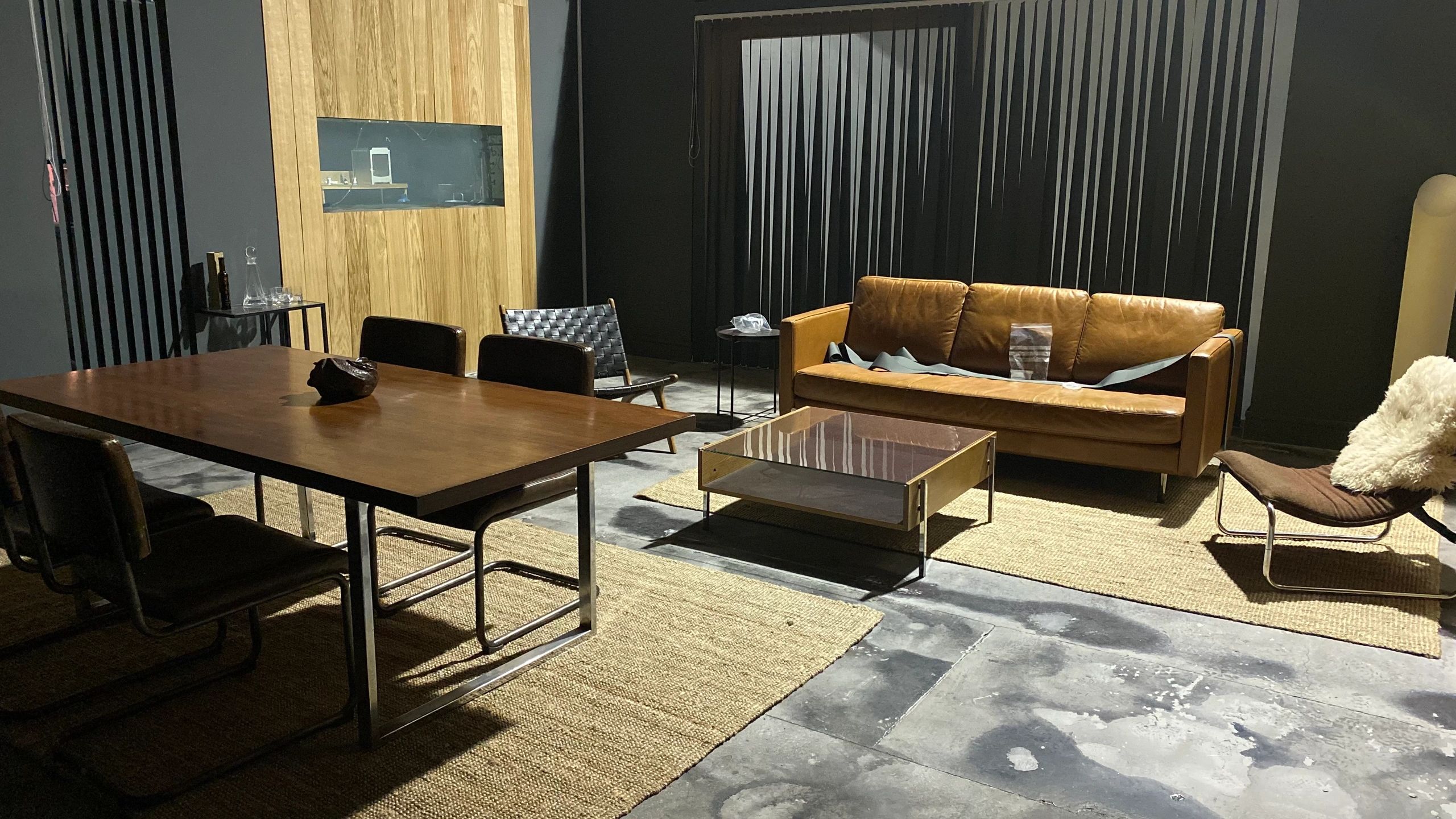 Modern living and dining room with leather sofa and wooden table.