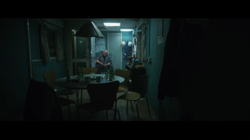 Man sitting alone in a dimly lit room.