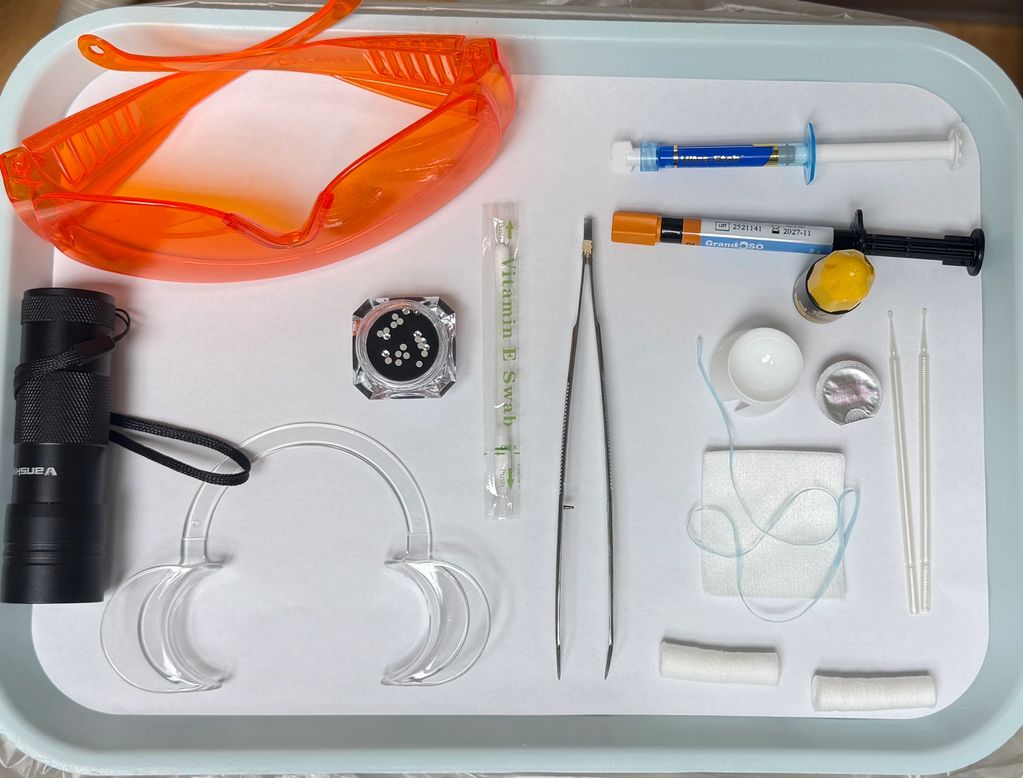 Dental tools and safety glasses arranged neatly on a white tray.