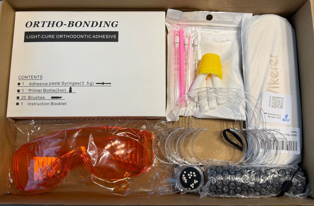 Orthodontic bonding kit with adhesive, brushes, protective glasses, and accessories.