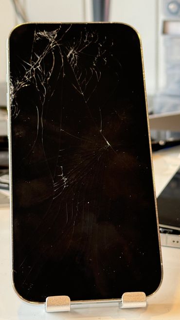 Smartphone with a cracked screen on display stand.