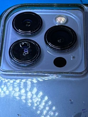 Close-up of a smartphone's triple camera setup with a cracked lens.