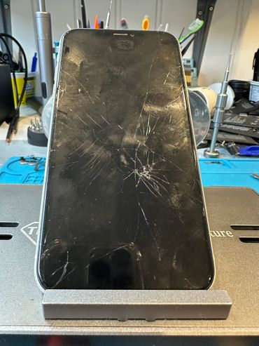 Smartphone with a cracked screen on a repair stand.