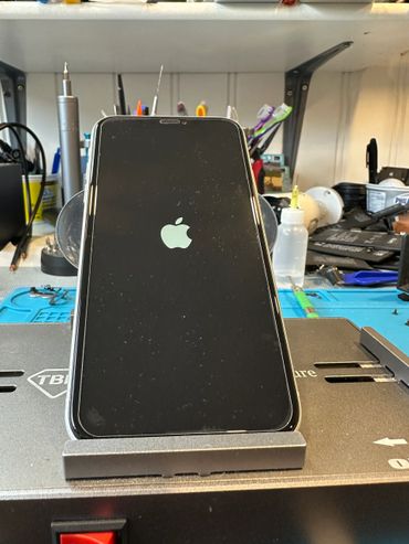 An iPhone displaying the Apple logo on a repair workstation.