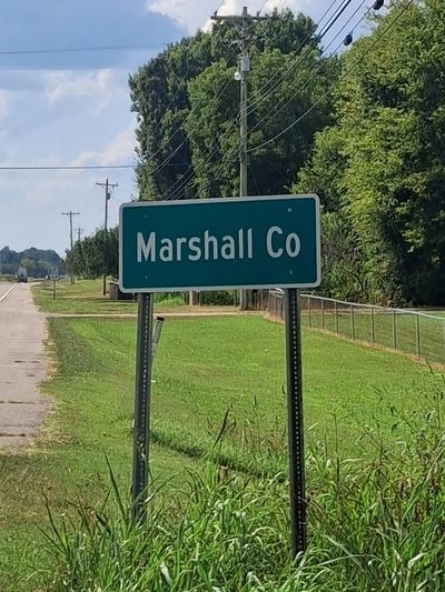 Road sign for Marshall Co by a roadside.