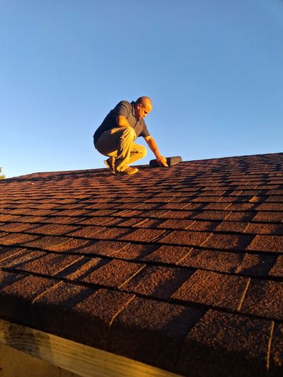 Licensed home inspector evaluating asphalt shingle roof during a home inspection.