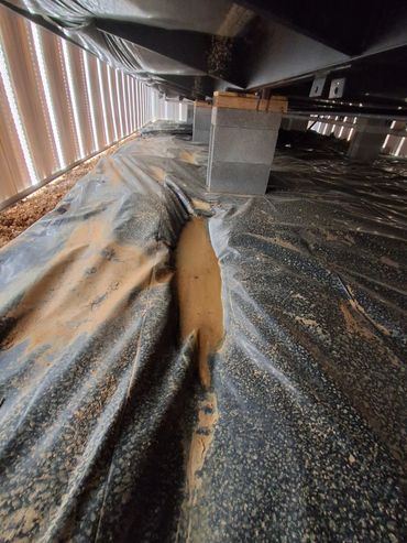 Standing water on vapor barrier under a manufactured home.