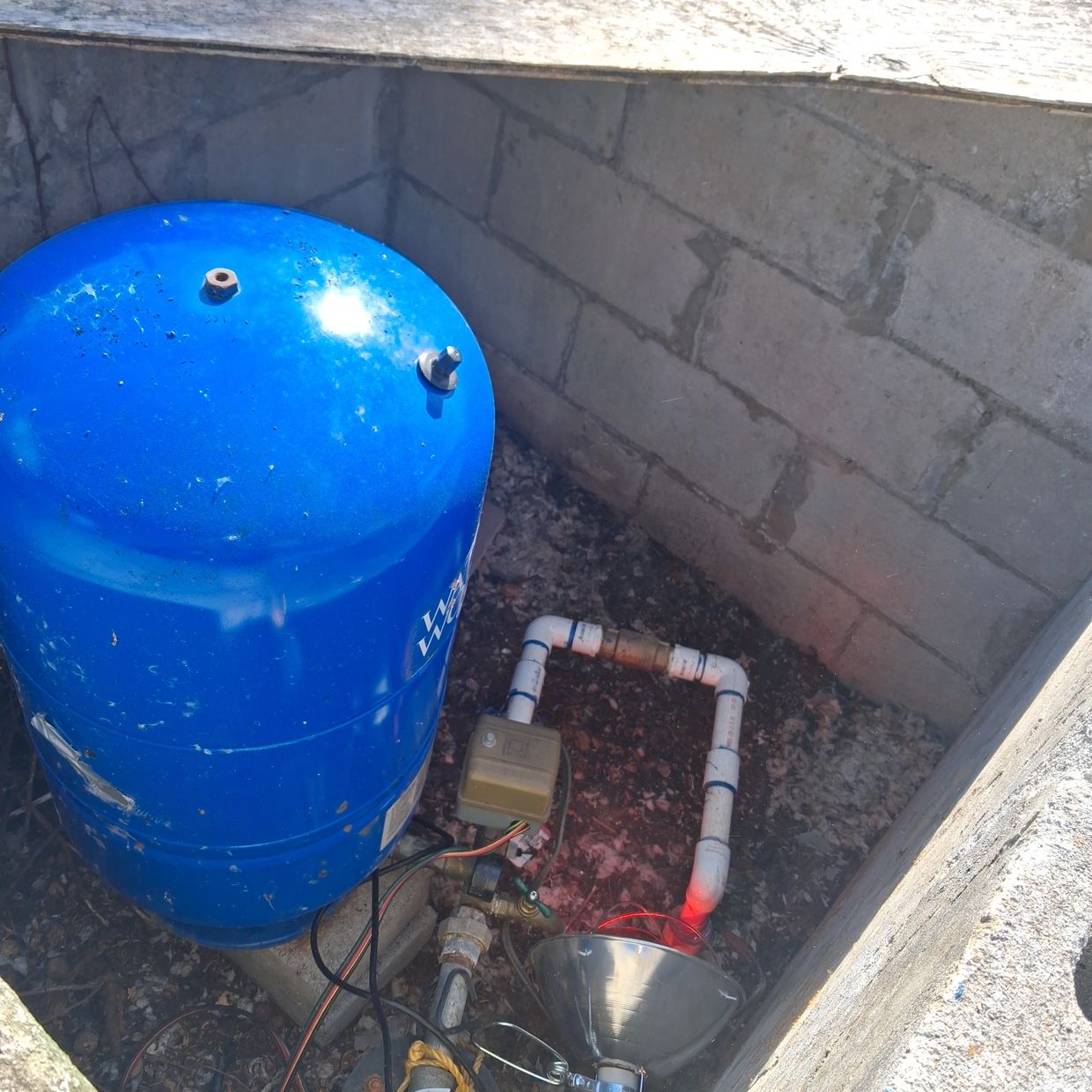 Blue well water pressure tank and PVC piping inside a concrete block well house in Huntland, TN.