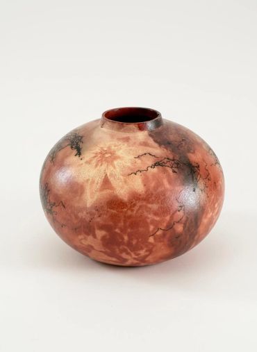 Round ceramic vase with orange and black patterns.