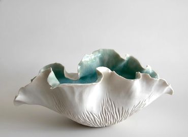 White ceramic bowl with turquoise interior and scalloped edges.