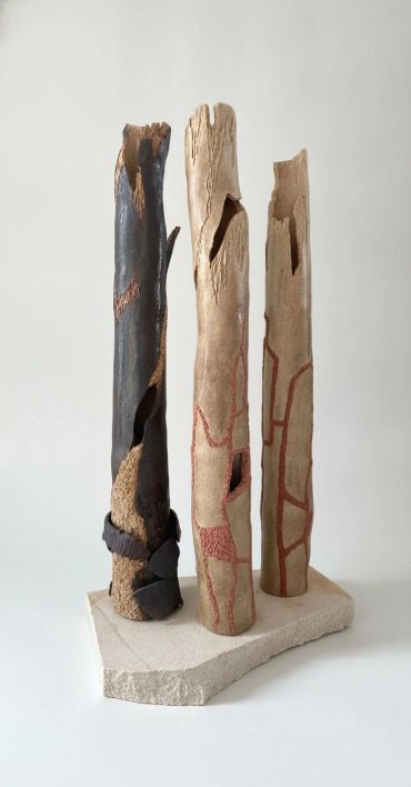 Artistic ceramic sculptures resembling tree trunks with textures and cutouts.