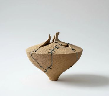 A cracked and repaired ceramic pot on a white background.