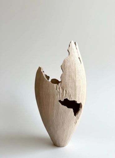 Artistic wooden sculpture with rough textures and holes.