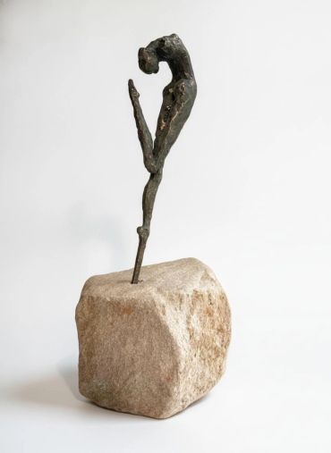 Abstract sculpture of a figure on a stone base.